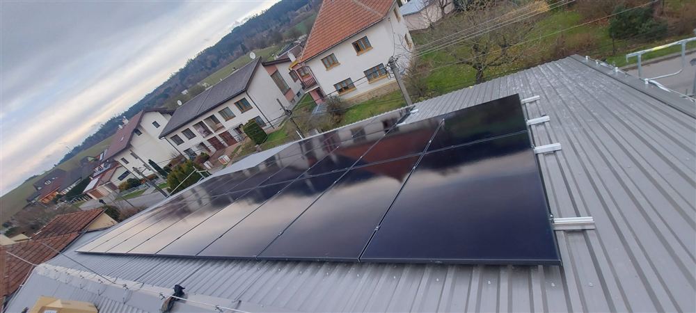 Černé panely na plechové střeše nad obcí
