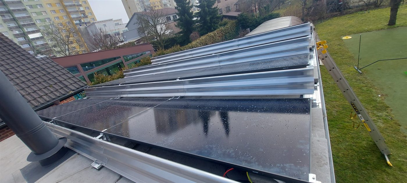 Řady černých panelů na ploché střeše na hliníkové konstrukci