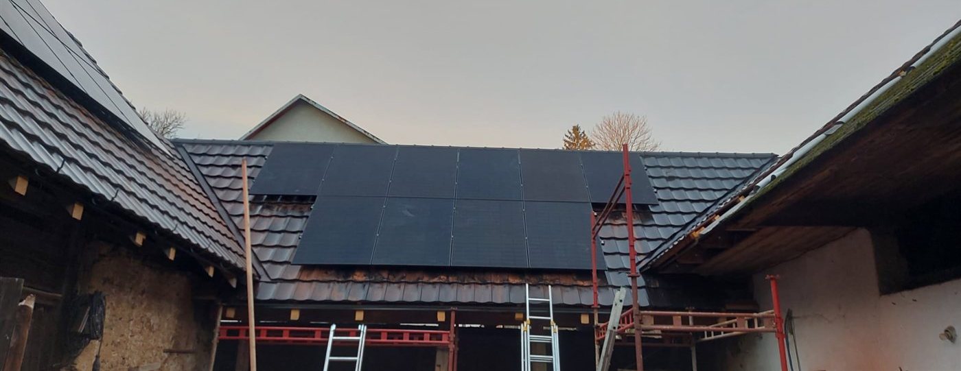 Panely na střeše mezi hospodářskými budovami, lešení a žebříky