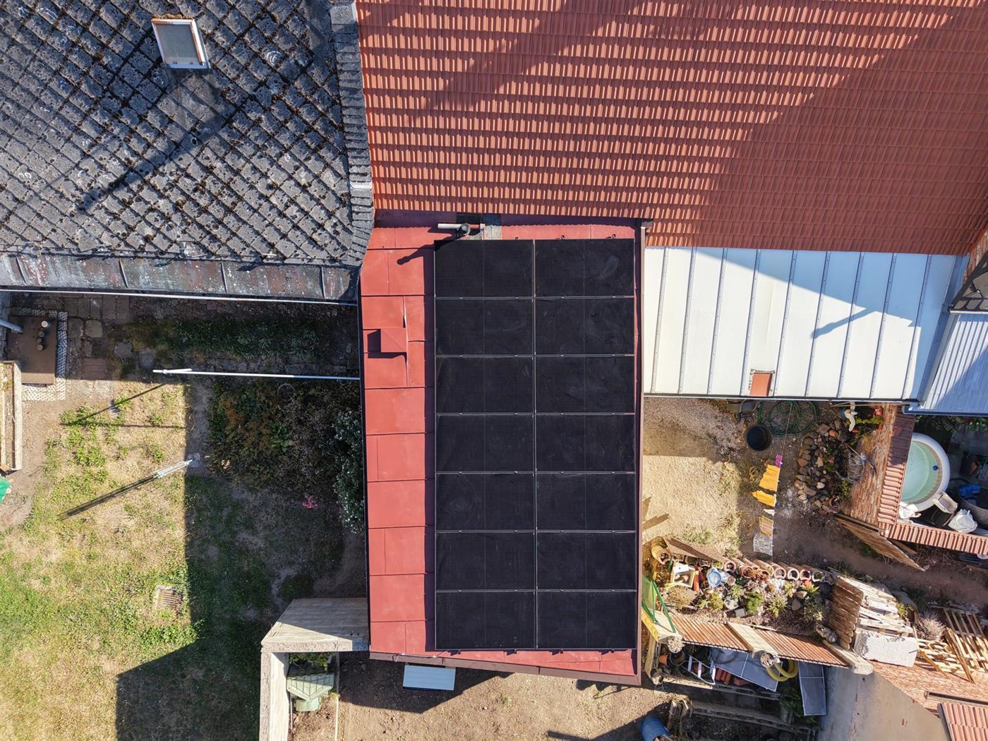 Pohled z dronu na panely na červené střeše přístavby